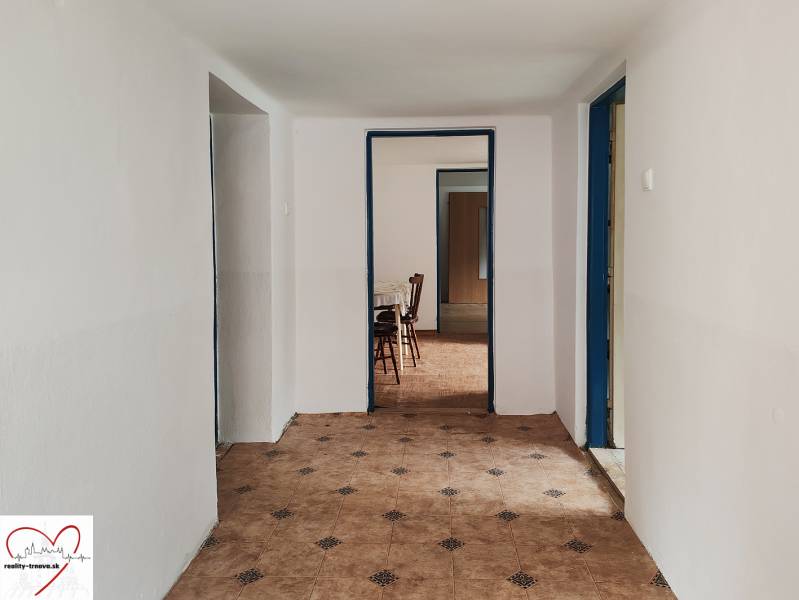 Ein Flur in einem Einfamilienhaus mit Fliesenboden und Möbeln im Hintergrund.