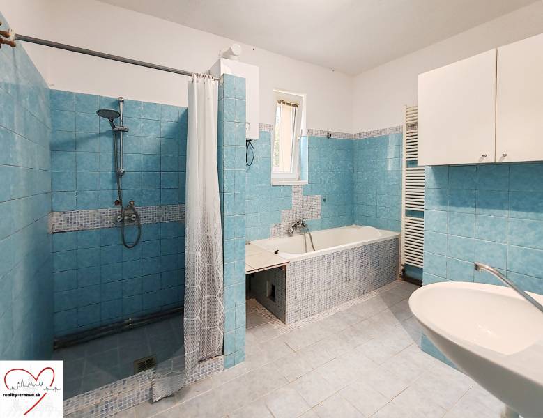 Ein Badezimmer in einem Einfamilienhaus mit blauen Fliesen, einer Dusche und einer Badewanne.