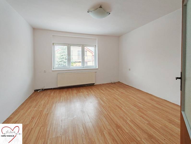Ein Zimmer in einem Einfamilienhaus mit einem Holzboden und einem großen Fenster.