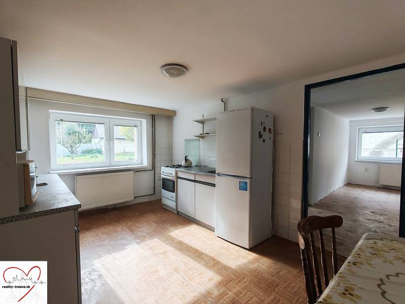 Eine Küche in einem Einfamilienhaus mit einem Boden in Holzoptik, ausgestattet mit Geräten und einem Esstisch.