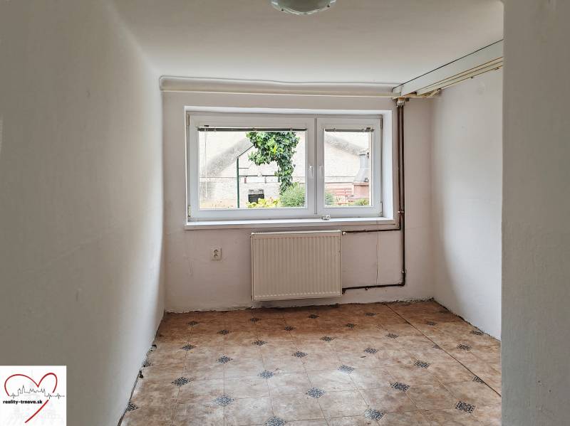 Kleine Zimmer mit hellen Wänden, großem Fenster und gemustertem Boden in einem Einfamilienhaus.