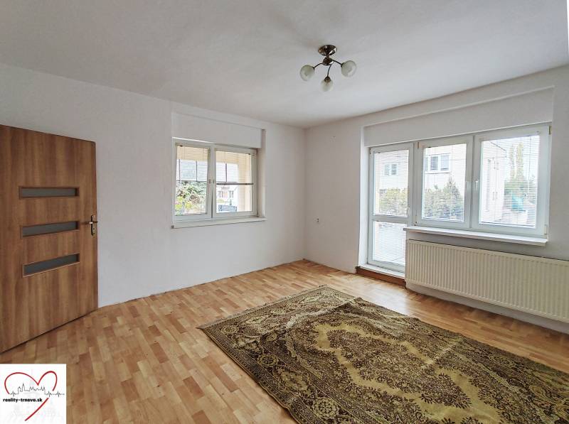 Ein Zimmer in einem Einfamilienhaus mit einem Boden in Holzoptik, einem Teppich und einem großen Fenster.