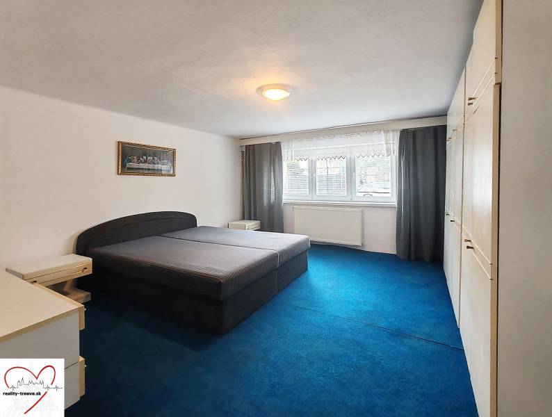 Ein Schlafzimmer in einem Einfamilienhaus mit einem großen Bett, einem blauen Teppich und einem Einbauschrank.