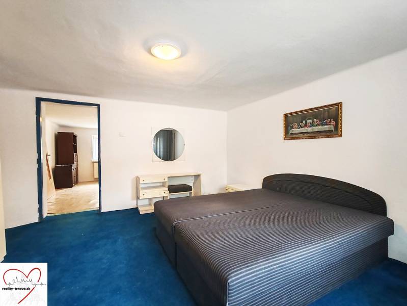 Schlafzimmer in einem Einfamilienhaus mit großem Bett, blauem Teppich und Bild an der Wand.