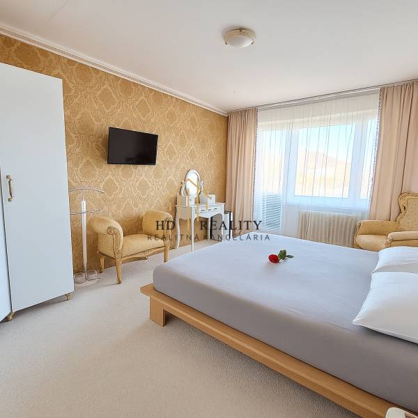 Schlafzimmer in einer 3-Zimmer-Wohnung mit elegantem Möbeln, goldener Tapete und weißem Teppich.