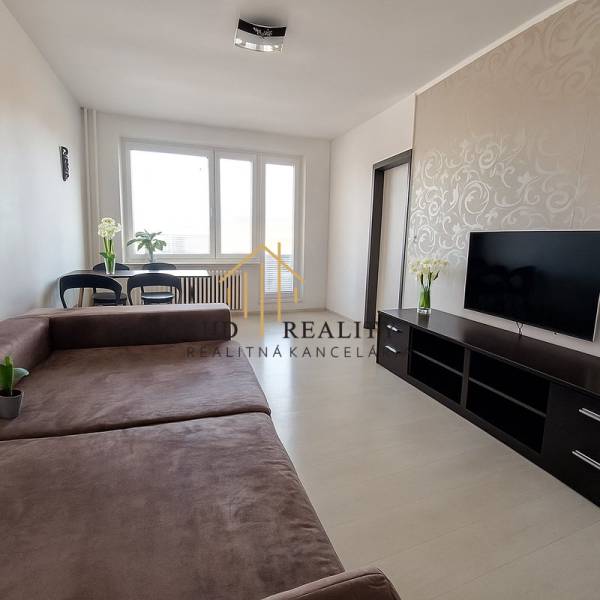 Wohnzimmer in einer 3-Zimmer-Wohnung mit großem Sofa, Fernseher und Boden in Holzoptik.