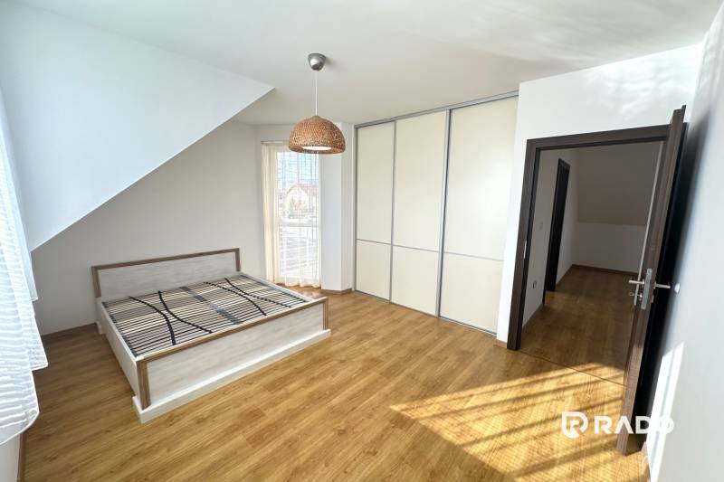 Ein Schlafzimmer in einem Einfamilienhaus mit einem Bett, einem Einbauschrank und einem Boden mit Holzdekor.