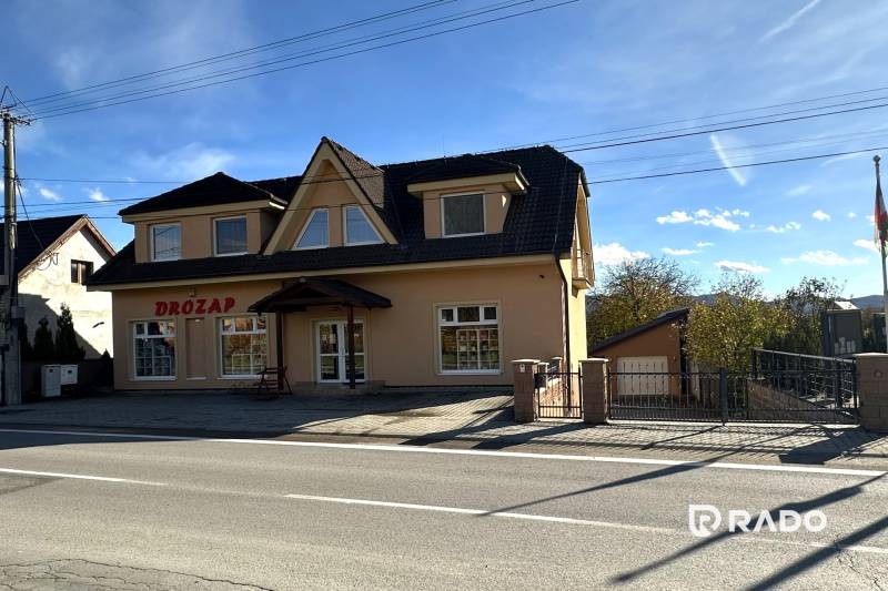 Ein Einfamilienhaus in Bolešov mit Dachgeschoss, großen Fenstern und einem Geschäftsraum im Erdgeschoss.