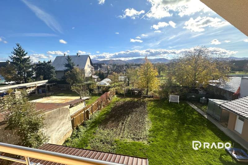 Ein Garten bei einem Einfamilienhaus in Bolešov mit Blick auf die Berge, Rasen und Bäume.