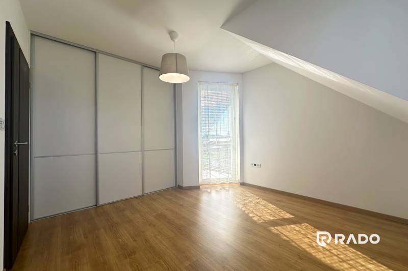 Innenraum eines Gebäudes mit Holzboden, Einbauschrank und Fenster mit Rollladen.