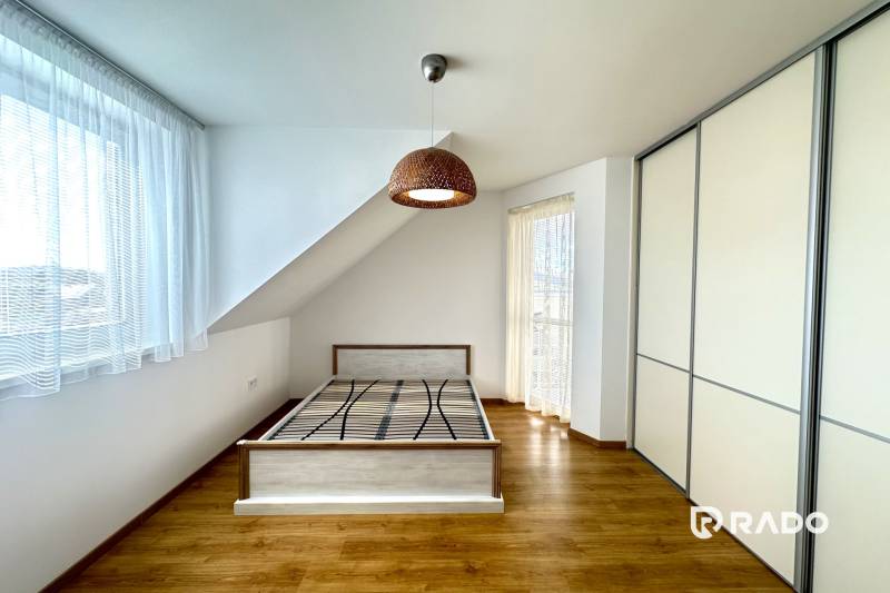 Helles Zimmer mit Bett, Einbauschrank und Holzboden in einem Einfamilienhaus.