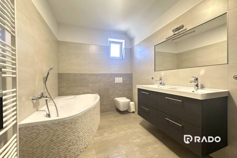 Badezimmer mit Badewanne, Doppelwaschbecken und Spiegel in einem Einfamilienhaus.