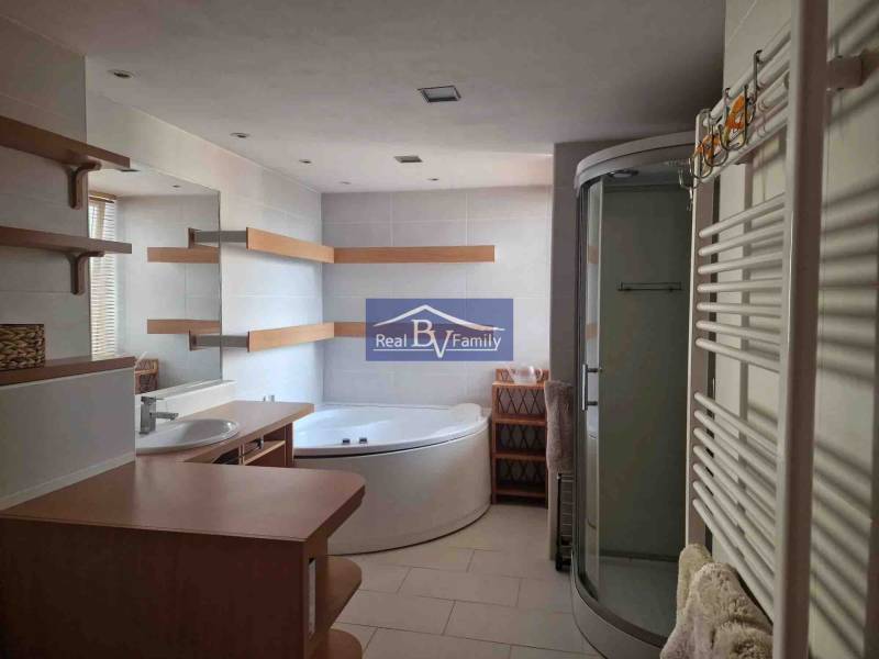 Badezimmer in einer 2-Zimmer-Wohnung, mit Badewanne, Dusche und Regalen.