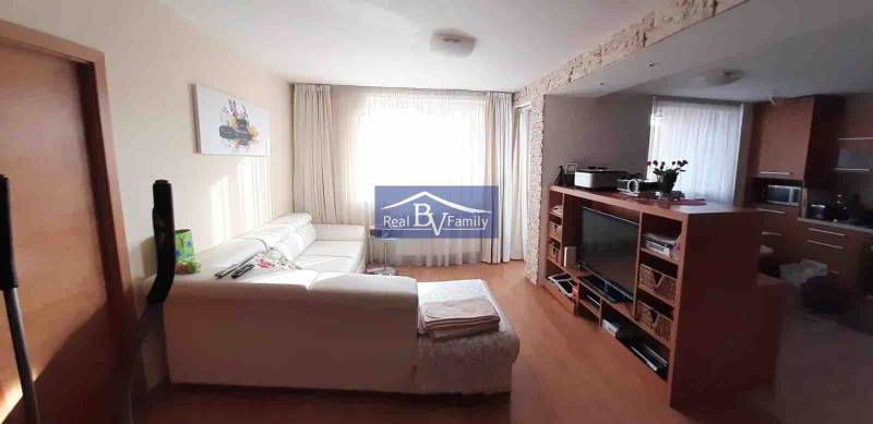 Wohnzimmer mit weißem Sofa und Fernseher, Holzboden, 2-Zimmer-Wohnung.