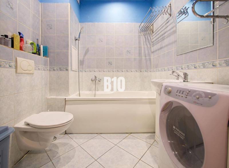 Badezimmer in einer 2-Zimmer-Wohnung mit Dusche, Waschbecken und Waschmaschine.