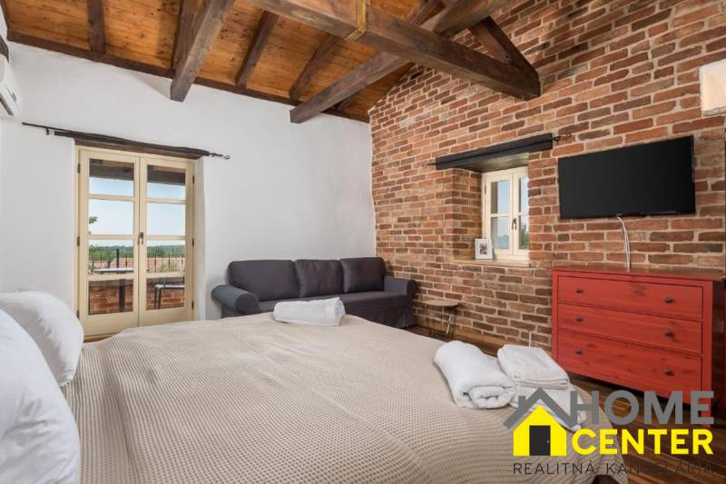 Schlafzimmer in einer Villa mit Ziegelwänden, Fernseher, Sofa und großem Bett.