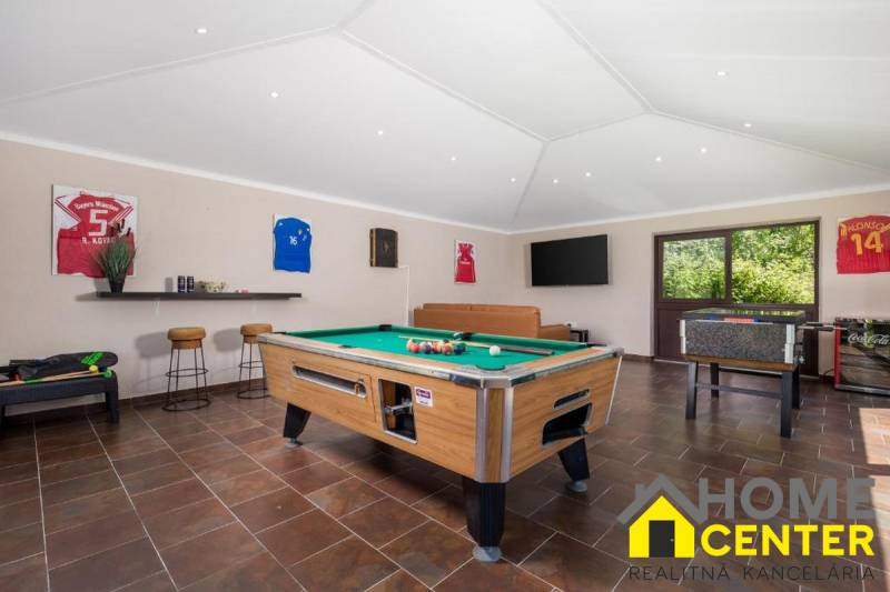 Innenraum einer Villa mit Billardtisch, Ledersofa und Holzboden.