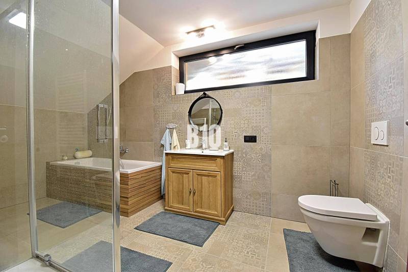 Badezimmer mit Badewanne, Dusche, Spiegel und Schrank in der Hütte. Helle Fliesen und Bodenbeläge.