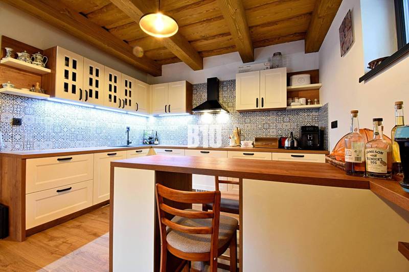 Eine Küche in einer Hütte mit Holzdecke, einem Boden mit Holzdekor und blauen Fliesen.