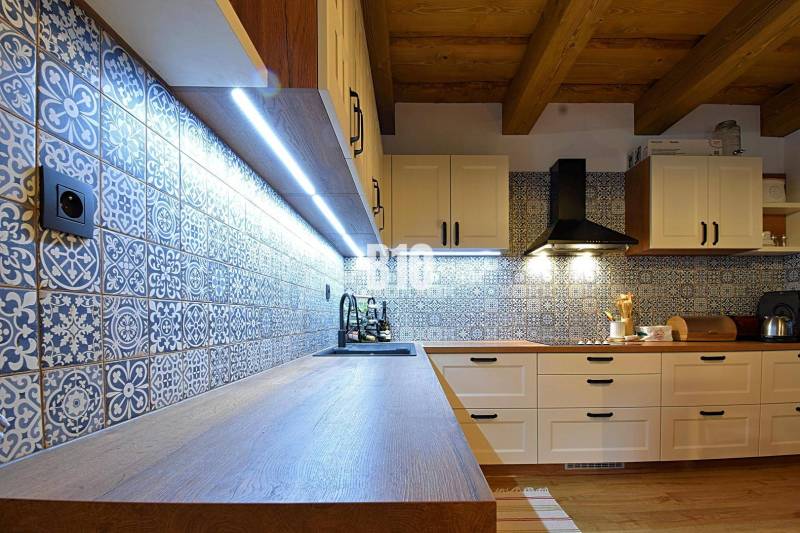 Küche in einer Hütte mit Fliesen und Holzboden, beleuchtet mit LED-Lichtern.