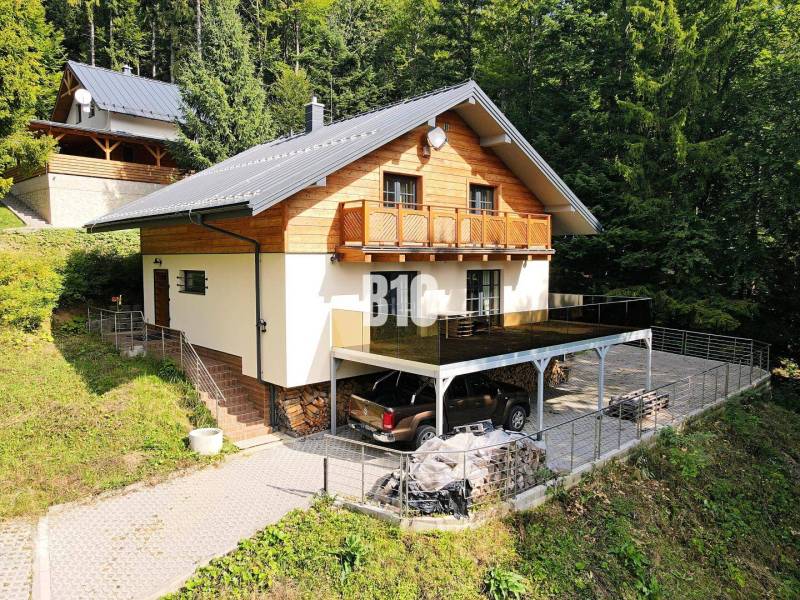 Eine Hütte in Terchová, umgeben von Wald, mit einem Parkplatz und einer Terrasse.