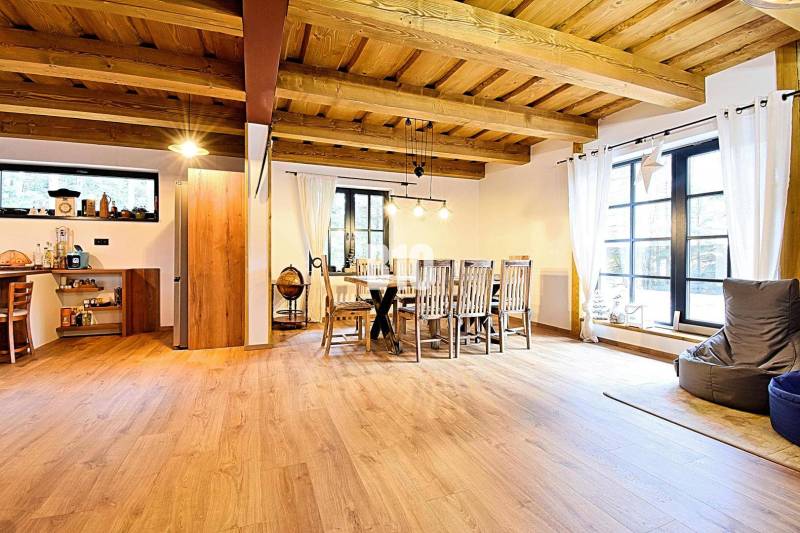 Offener Innenraum in einer Hütte mit Holzboden und Esstisch.