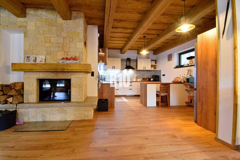 Innenraum der Hütte mit Kachelkamin, Holzdecke und Boden mit Holzdekor.