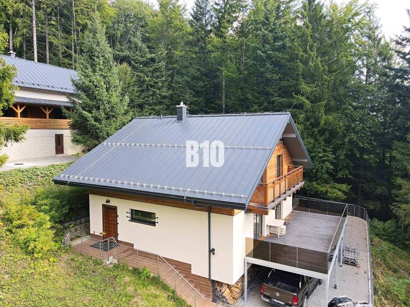 Eine Hütte in Terchová, umgeben von Wäldern, mit großer Terrasse und Parkplatz.