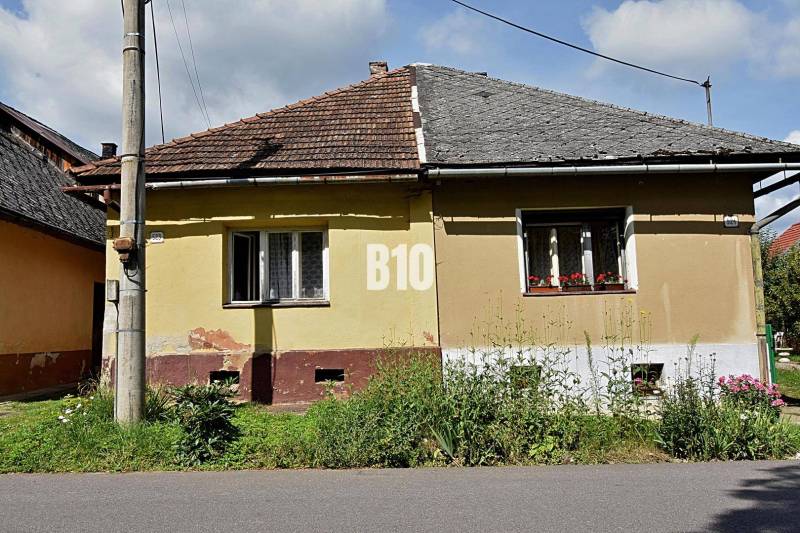 Ein gelbes Einfamilienhaus in Partizánska Ľupča mit einem schrägen Dach und einem angrenzenden Garten.