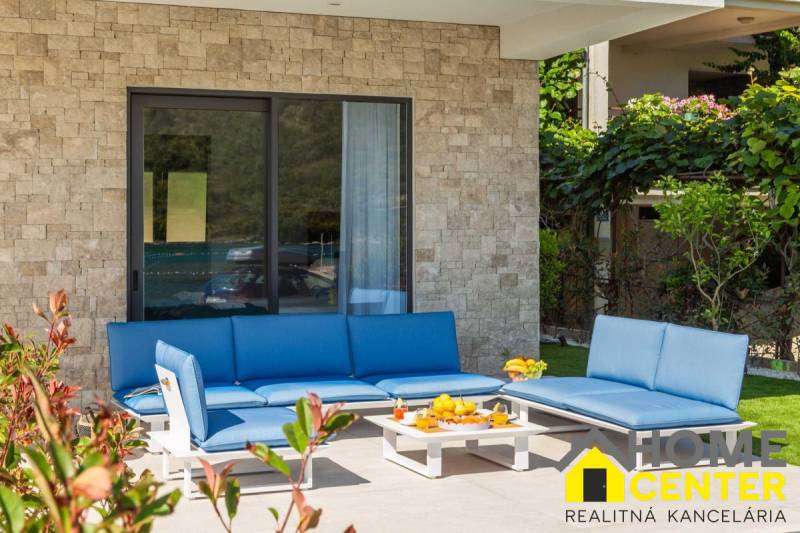 Außenbereich der Villa in Bale mit blauen Gartenmöbeln und einer Steinmauer.