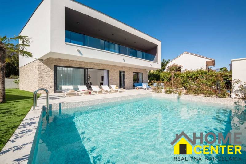 Eine Villa in Bale mit Pool und Liegestühlen, umgeben von Grün und blauem Himmel.