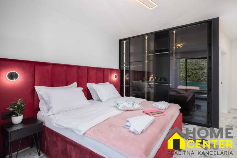 Schlafzimmer in der Villa mit einem Bett, das mit rotem Samt gepolstert ist, und einem Glasschrank.