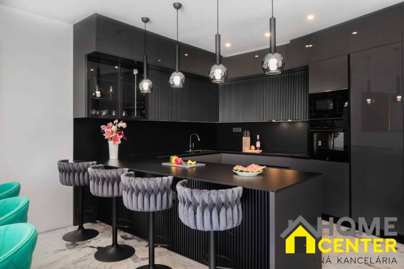 Schwarze Küche in einer Villa mit Marmorboden und luxuriösen Stühlen.