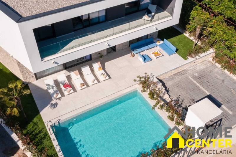 Eine Villa in Bale mit Pool, Liegestühlen und einer gemütlichen Außensitzgelegenheit.