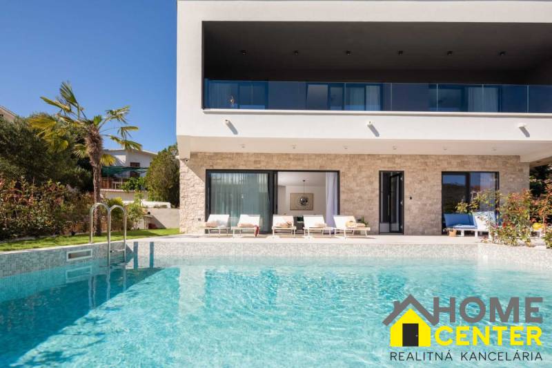 Villa in Bale mit Pool, Palmen, Terrasse und Liegestühlen im Hintergrund.