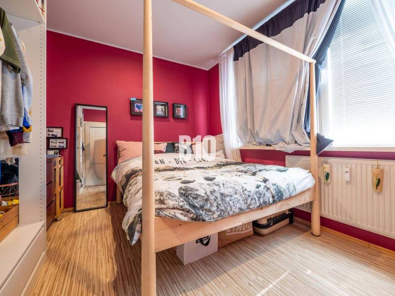 Schlafzimmer mit Bett, Spiegel und Holzboden in einer 4-Zimmer-Wohnung.