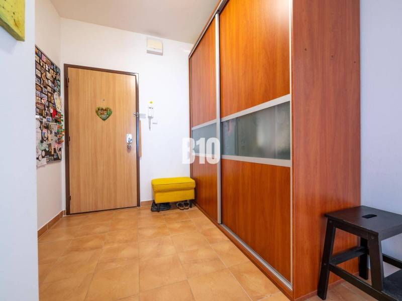 Flur in einer 4-Zimmer-Wohnung mit Fliesen und Einbauschrank.