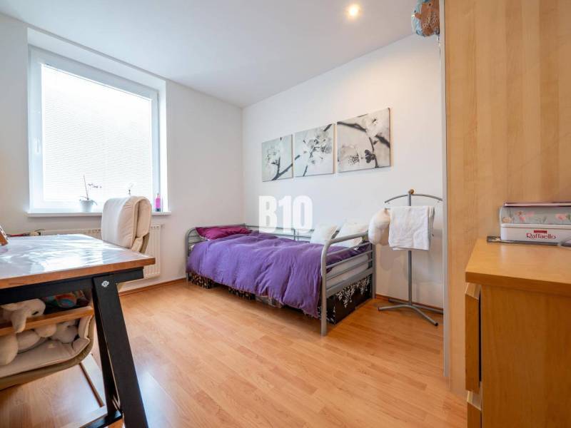 Schlafzimmer in einer 4-Zimmer-Wohnung mit Holzboden und violetter Tagesdecke.