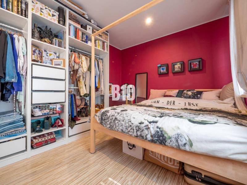 Schlafzimmer mit Bett, Holzboden und offenem Kleiderschrank in einer 4-Zimmer-Wohnung.