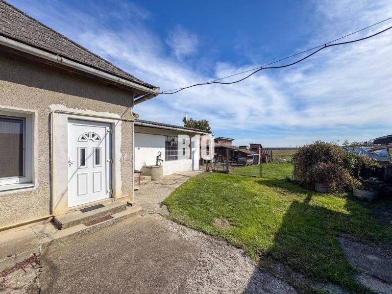 Ein Einfamilienhaus in Ondrejovce mit Hof, Brunnen und Blick auf die offene Landschaft.