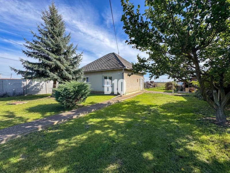 Ein Einfamilienhaus in Ondrejovce, umgeben von grünem Rasen und Bäumen in einem geräumigen Garten.