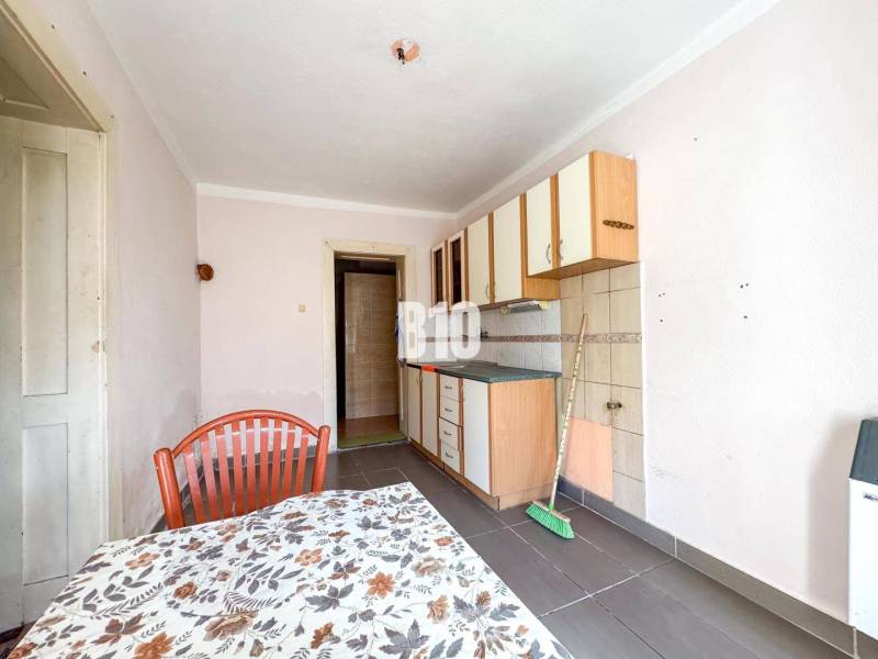 Küche mit einfachen Schränken, Fliesen und Tisch in einem Einfamilienhaus.