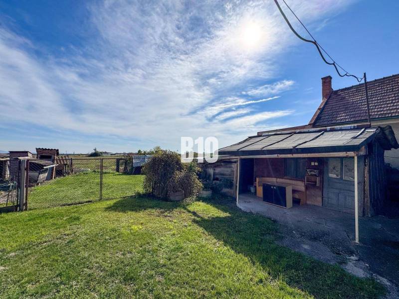 Ein Einfamilienhaus in Ondrejovce mit Garten, Unterstand und Blick auf die Natur bei sonnigem Wetter.
