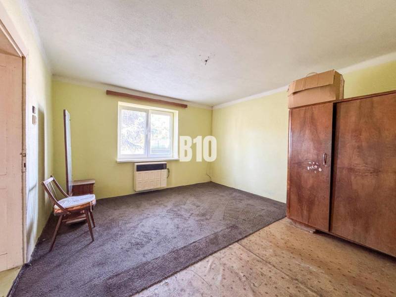 Einfaches Zimmer in einem Einfamilienhaus mit Teppichboden und Holzmöbeln.