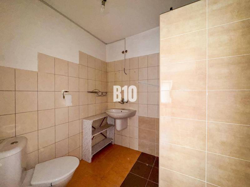 Ein Badezimmer in einem Einfamilienhaus mit beigen Fliesen und weißen Sanitäreinrichtungen.