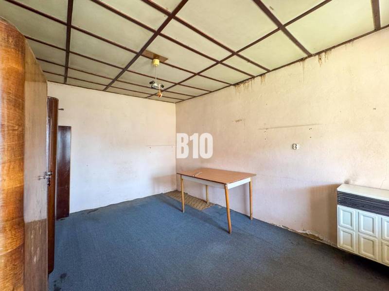 Ein Zimmerinterieur in einem Einfamilienhaus, das einen Teppich, Schränke und einen Tisch enthält.