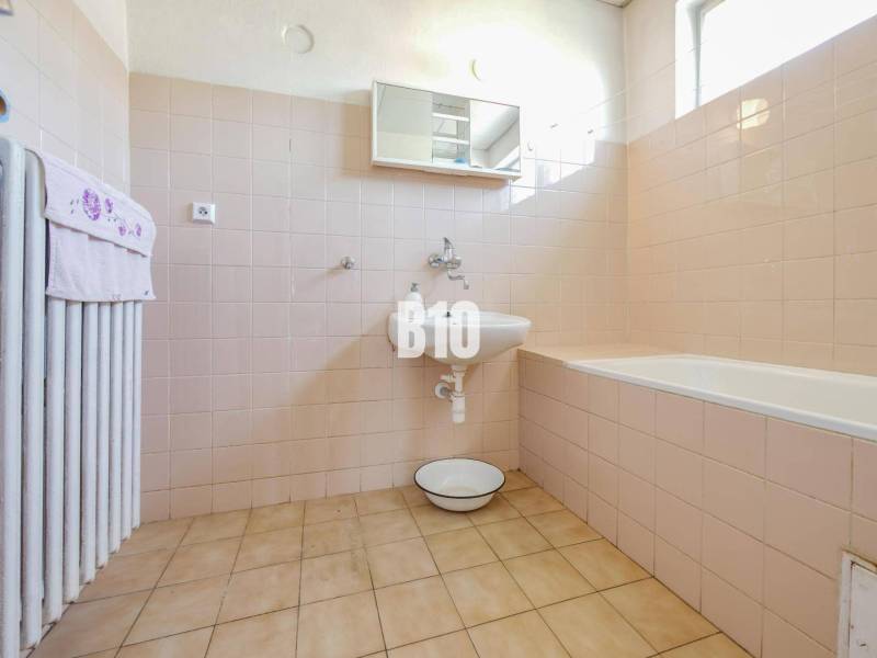 Ein Badezimmer in einem Einfamilienhaus mit einer Badewanne und hellen Fliesen an den Wänden.