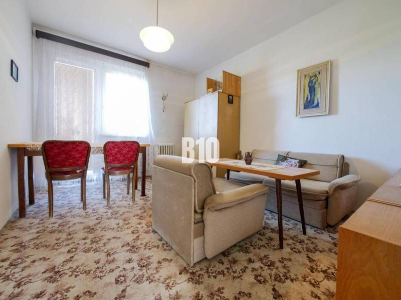 Wohnzimmer in einem Einfamilienhaus mit Teppich und roten Stühlen.