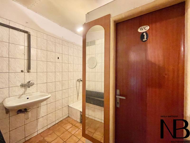 Badezimmer in einem Einfamilienhaus mit Waschbecken, Duschkabine und einer Tür mit der Aufschrift 