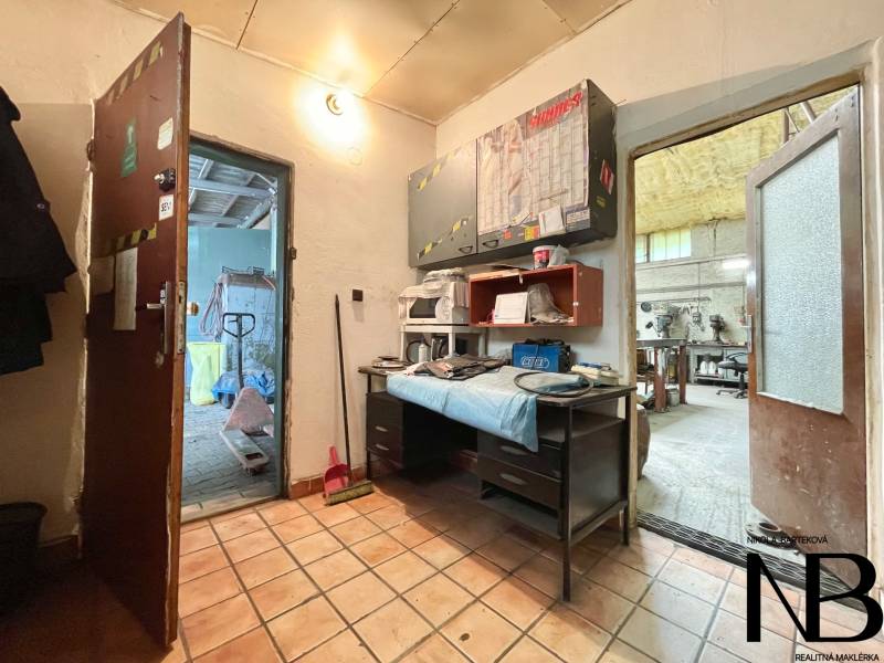 Innenraum von Geschäftsräumen mit Fliesenboden, Arbeitstisch und Werkzeugen auf den Regalen.